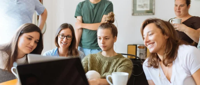 A diverse group of adults at work, enjoying a casual meeting indoors with focus and smiles.